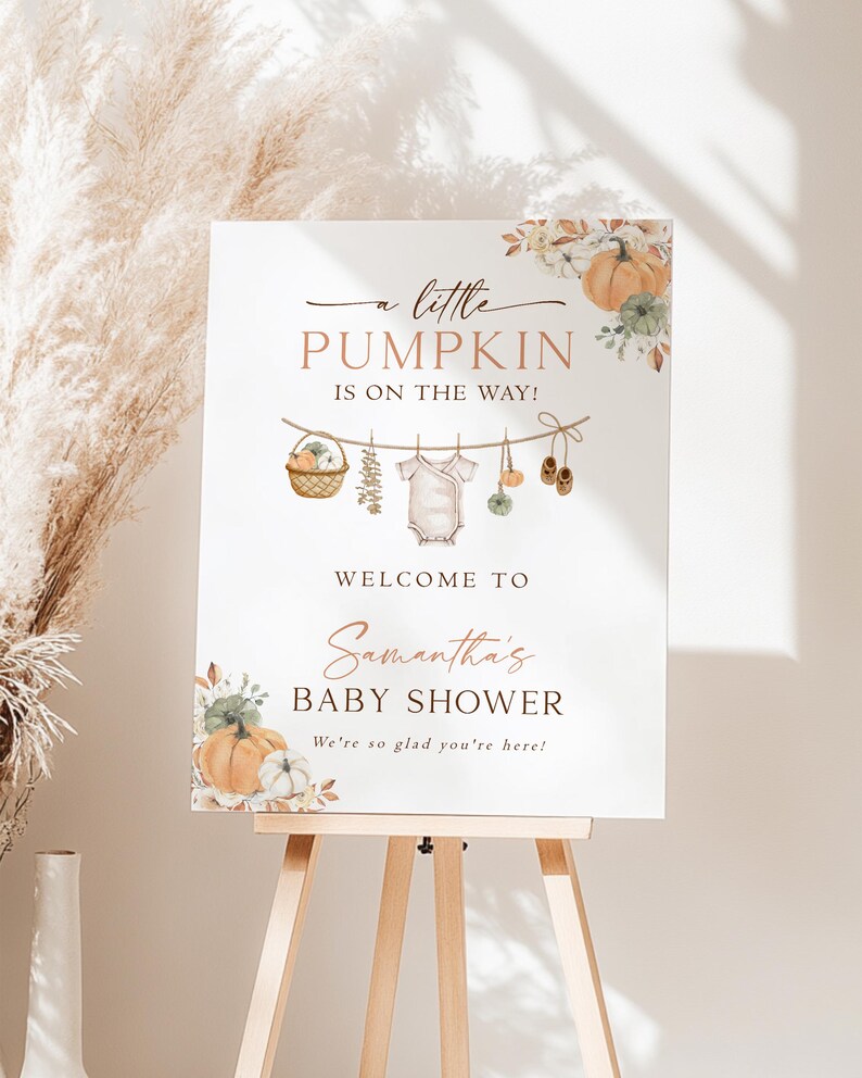 May include: A white rectangular sign featuring the text A little PUMPKIN IS ON THE WAY! WELCOME TO Samantha's BABY SHOWER We're so glad you're here! The design includes watercolor illustrations of pumpkins, a basket, baby clothes, and shoes.