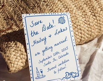 Może przedstawiać: Prostokątna biała karta z niebieskim odręcznym tekstem Save the Date! Hailey & Lukas are getting married! September 20th, 2025 Santa Fe, Colorado Formal invitation to follow! z niebieskimi ikonami kuli dyskotekowej, wina i kokardy.