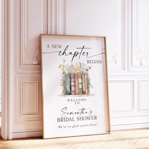 May include: A framed poster with the text "A New Chapter Begins" and "Welcome to Samantha's Bridal Shower." The artwork features a stack of books with flowers. The poster is 18x24 inches.