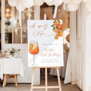 May include: A white sign on a wooden easel with the text "A Spritz Older" and "Welcome to Hailey's 30th Birthday". The sign features an illustration of an orange cocktail and orange slices.