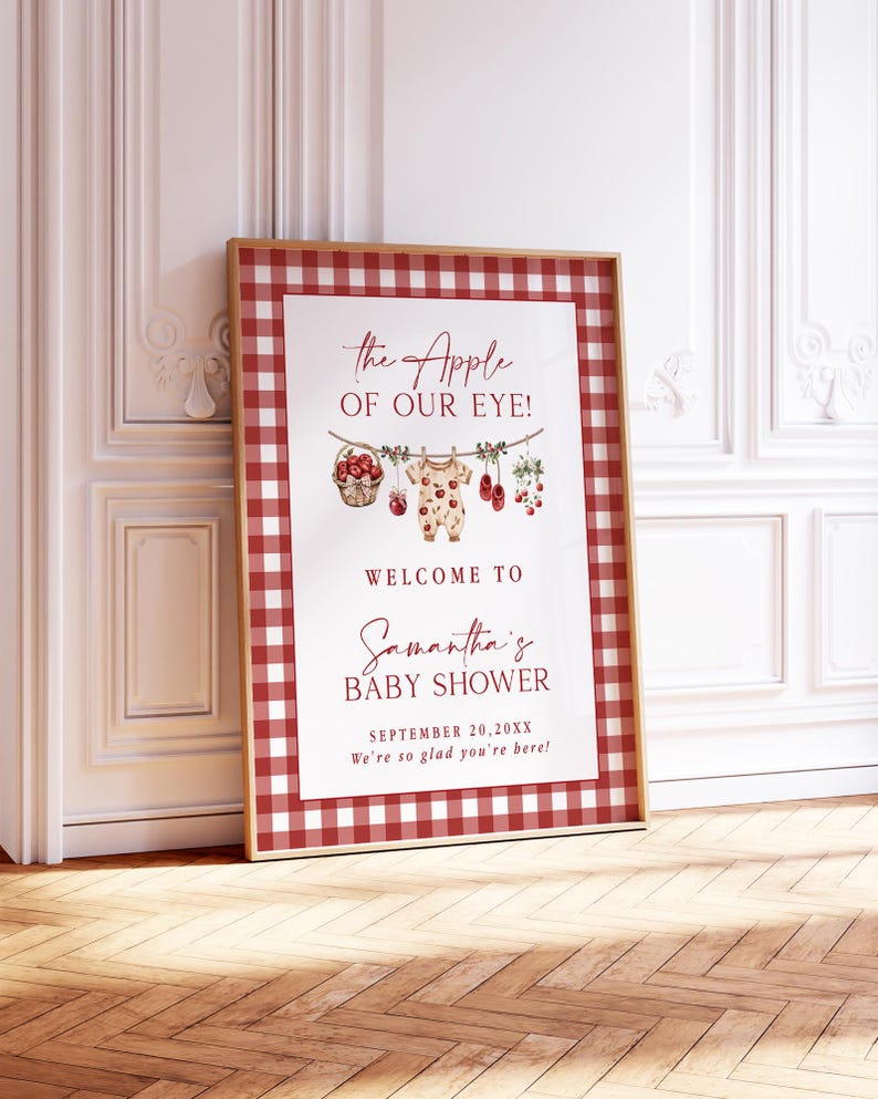 Puede incluir: Un letrero enmarcado para baby shower con un borde a cuadros rojo y blanco. El letrero dice "the Apple of our Eye!" y "Welcome to Samantha's Baby Shower" con la fecha. El dise&ntilde;o incluye ilustraciones de manzanas y ropa de beb&eacute;.