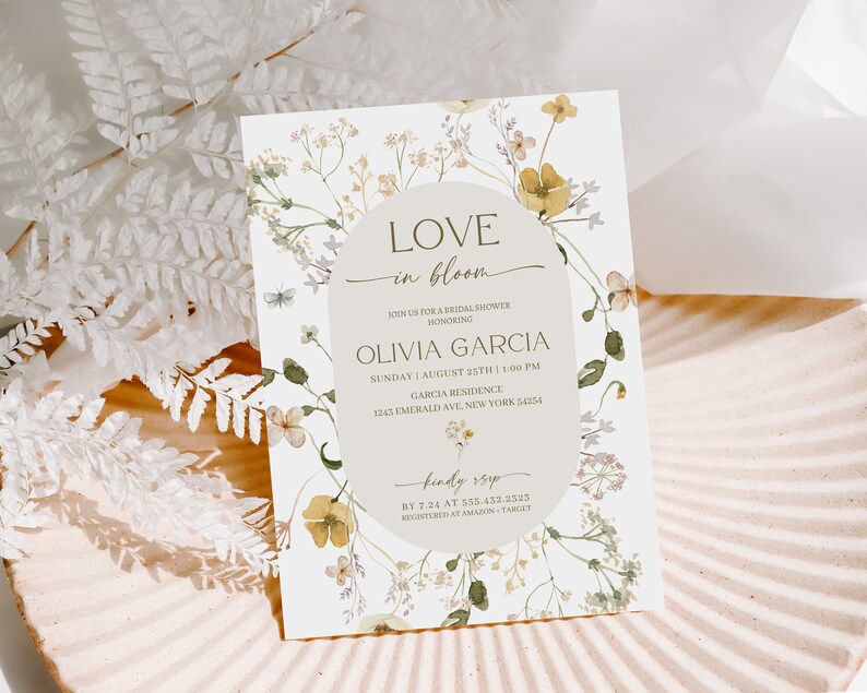 K&ouml;nnte beinhalten: Eine florale Brautduscheinladung mit einem Aquarelldesign aus gelben und gr&uuml;nen Blumen. Der Text lautet "Love in Bloom" und enth&auml;lt den Namen der Braut, Datum, Uhrzeit und Ort. Die Einladung enth&auml;lt auch die RSVP-Informationen.