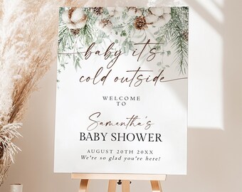 May include: A rectangular white sign featuring a winter-themed illustration of pine branches, pinecones, and cotton bolls at the top. The text reads: baby its cold outside, WELCOME TO Samantha's BABY SHOWER, AUGUST 20TH 20XX, We're so glad you're here!