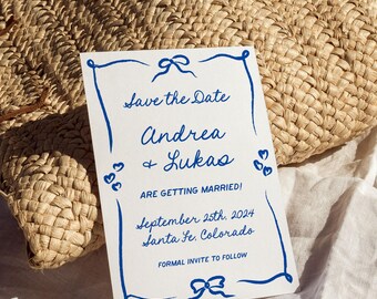 Może przedstawiać: Biała prostokątna karta Save the Date z niebieskimi, ręcznie rysowanymi obramowaniami, kokardkami i sercami. Tekst brzmi: Save the Date, Andrea & Lukas ARE GETTING MARRIED! September 25th, 2024 Santa Fe, Colorado, FORMAL INVITE TO FOLLOW.