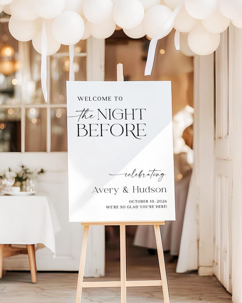 Pu&ograve; includere: Un cartello bianco su un cavalletto di legno con la scritta "WELCOME TO THE NIGHT BEFORE" e i nomi "Avery & Hudson" con la data 10 ottobre 2026. Palloncini bianchi e nastri decorano la parte superiore. Il cartello d&agrave; il benvenuto agli ospiti.