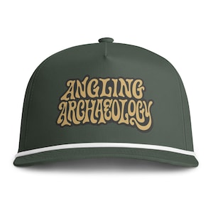 Könnte beinhalten: Eine dunkel olivgrüne Baseballkappe mit einer weißen Kordelverzierung entlang der Basis der Krone. Auf der Vorderseite der Kappe befindet sich der Text ANGLING ARCHAEOLOGY in einer stilisierten, fetten, beigen Schrift mit dunkler Umrandung.