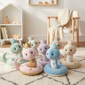Peut inclure: Collection de peluches en forme de serpent aux couleurs pastel, chacune ornée d'une couronne. Les serpents sont enroulés, avec des détails en forme de cœur et des étoiles. Ils sont disposés sur un tapis crème.