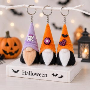 May include: Three plush gnome keychains with metal rings. The first has a lavender hat with a white skull, the second an orange hat with a purple flower, and the third an orange hat with a black bat and heart. They have white or tan beards.