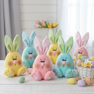 May include: A collection of colorful Easter bunny plushies in pastel shades of yellow, blue, pink, and green. Each bunny has long ears with polka dots, a pink nose, and embroidered facial features. A white basket filled with Easter eggs is also present.