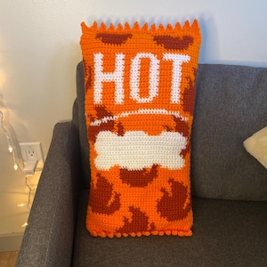 Puede incluir: Almohada de crochet naranja y blanca con forma de sobre de salsa picante con la palabra "HOT" en letras blancas.