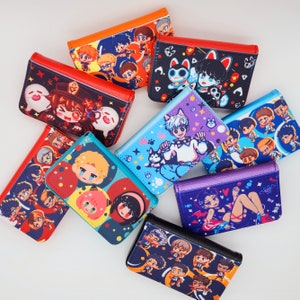 May include: A collection of colorful, rectangular wallets with various anime-style character designs. The wallets feature red, orange, blue, purple, and black accents. Each wallet has a different illustration, including characters with cat ears, and other cartoon figures.