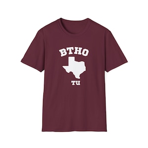 May include: Burgundy t-shirt with a white outline of the state of Texas and the text "BTHO TU" in white.