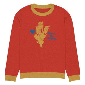 May include: Red long-sleeve sweater with a yellow ribbed collar and cuffs. The sweater features a blue heart and a graphic of wheat stalks with the text "Wave the Wheat".