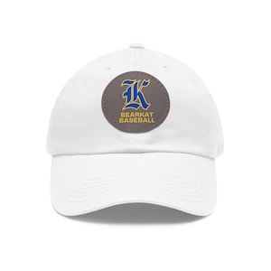 May include: White baseball cap with a curved brim. The cap features a circular patch with a blue and gold "K" logo and the words "BEARKAT BASEBALL" in gold lettering. The cap is a classic, casual style.