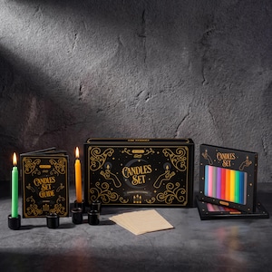 May include: A candle set with a black box featuring gold accents and the words "Candles Set". The set includes a guide, candles in various colors, and black candle holders. The candles are lit, casting a warm glow.