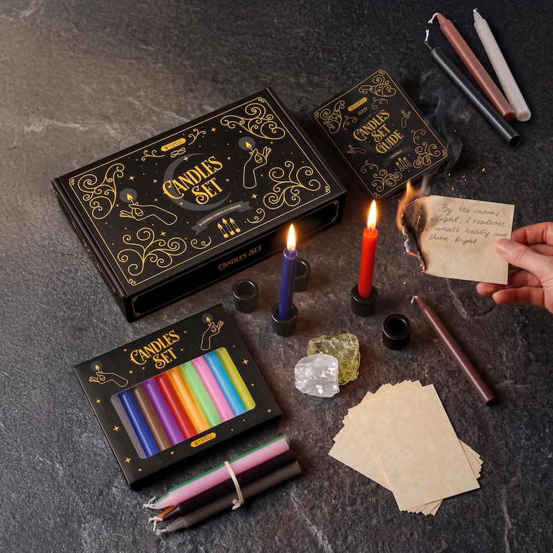 May include: A candle set with a black box featuring gold accents and the words "Candles Set". The set includes various colored candles, a guide, and other accessories. Two candles are lit, one blue and one red.