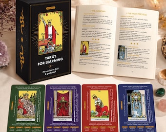 Könnte beinhalten: Eine schwarze Tarot-Kartenschachtel mit der Aufschrift Tarot for Learning, ein offenes Begleitbuch und vier Tarotkarten: Die Herrscherin in Grün, Die Gerechtigkeit in Lila, Die Kraft in Rot und Die Hohepriesterin in Blau mit Text.