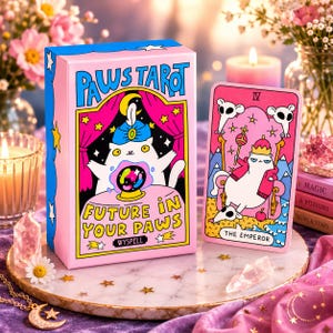 May include: A Paws Tarot deck box and a single tarot card titled The Emperor. The pink box features a white cat with a blue turban and a crystal ball with the text Paws Tarot and Future In Your Paws. The card shows a white cat on a throne.