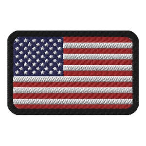 May include: A small embroidered American flag patch with a black border. The flag is red, white, and blue.