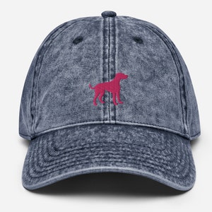 May include: A dark blue denim baseball cap with a pink dog silhouette embroidered on the front.