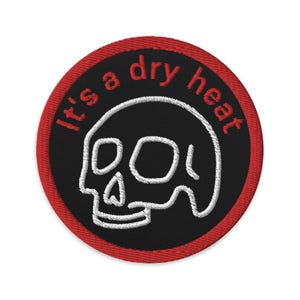 May include: Red and black embroidered patch with a white skull and the text "It's a dry heat".