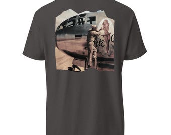 May include: Dark gray t-shirt featuring a vintage-style graphic of a bomber plane with a pin-up girl and the text "Little G". The design includes a man in a military uniform. The shirt is made of a soft, comfortable material.