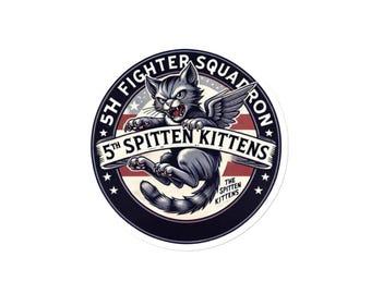 May include: A black and white circular sticker with a cartoon cat with wings flying in front of an American flag. The text "5th Fighter Squadron" and "5th Spitten Kittens" are on the sticker.