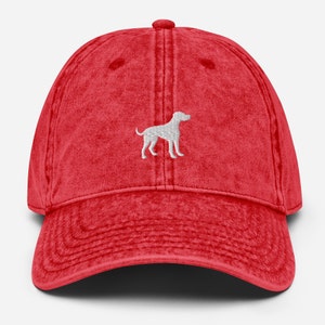 May include: Red vintage washed cotton baseball cap with a white embroidered silhouette of a dog.