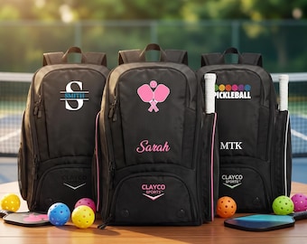 Könnte beinhalten: Drei schwarze Rucksäcke für Pickleball-Ausrüstung, jeder mit individueller Personalisierung. Die linke Tasche zeigt einen großen Buchstaben S mit dem Namen Smith. Die mittlere Tasche zeigt rosa Pickleball-Schläger und den Namen Sarah. Die rechte Tasche trägt den Text Pickleball und MTK. Alle Taschen enthalten das Clayco Sports-Logo.