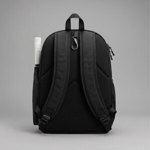 May include: A black backpack featuring padded shoulder straps with a mesh back panel, a top carry handle, and a black hook attachment. A white-handled racket is stored in a side pocket, and a black mesh pocket is visible on the opposite side.