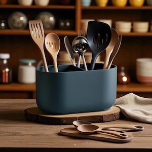 May include: A dark teal utensil holder containing a variety of kitchen tools, such as wooden spatulas, spoons, and a black slotted spatula. The holder is on a wooden surface with more wooden spoons and a chopping board.