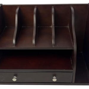 May include: A dark brown wooden desk organizer featuring three vertical slots on the top shelf, an open middle shelf, and a single bottom drawer with two small silver-toned knobs. The unit has curved side panels and a smooth, dark finish throughout.