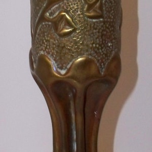 May include: A vintage brass vase with a textured surface and floral relief design. The vase has a bulbous base and a slender, elongated neck. The brass has a warm, aged patina, adding to its antique charm.