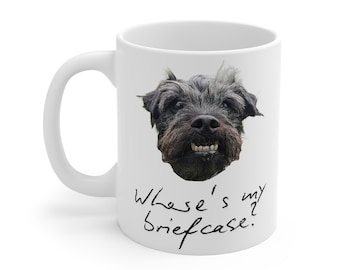 May include: White ceramic mug featuring a close-up of a black dog's face with visible teeth. The mug has the handwritten text "Where's my briefcase?" in black cursive script.