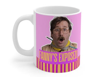 May include: A white ceramic mug featuring a graphic of a person with brown hair, glasses, and a mustache, wearing a tan shirt and yellow neckerchief. The text FANNY'S EXPOSED! appears in yellow on a purple background above vertical stripes.