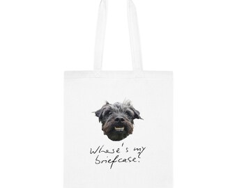 May include: White tote bag featuring a smiling dog's face with the text "Where's my briefcase?" in a handwritten font. The dog has dark fur and visible teeth. The bag has two white handles.