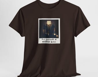 May include: A dark brown short-sleeve t-shirt featuring a central graphic print of a polaroid-style photograph. The image shows a group of figures standing before a bright window, with the text THE POSSESSION OF BUTTON HOUSE printed below.