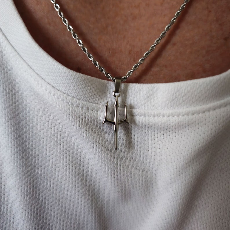 May include: A silver chain necklace with a trident pendant.