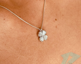 May include: A silver necklace featuring a four-leaf clover pendant. The pendant has a white, pearlescent finish and a small, clear gemstone at its centre. The chain is a delicate box chain style.