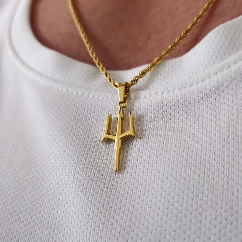 May include: A gold chain necklace with a gold trident pendant.