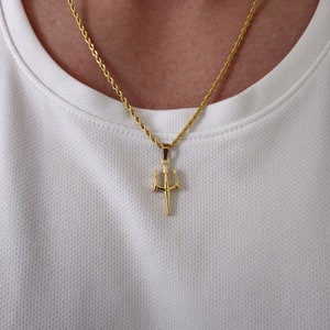 May include: A gold chain necklace with a trident pendant.