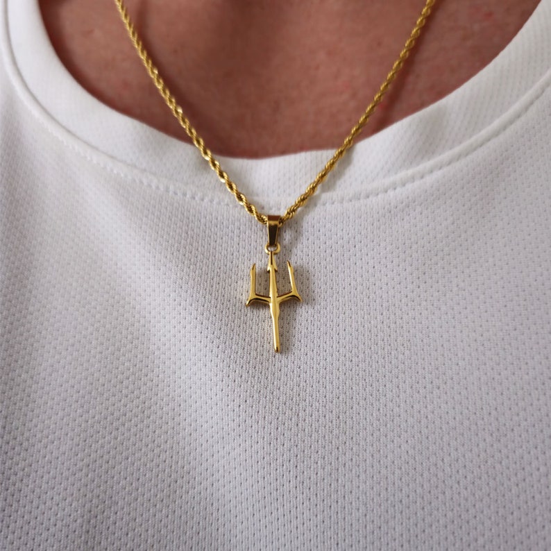 May include: A gold chain necklace with a gold trident pendant.