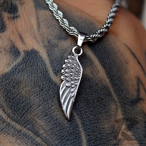 May include: A silver chain necklace with a detailed silver wing pendant. The pendant is a single wing with a textured surface.