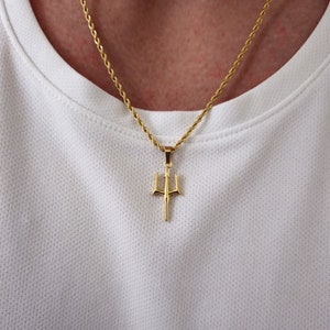 May include: A gold chain necklace with a trident pendant. The chain is a rope style and the pendant is a simple design.
