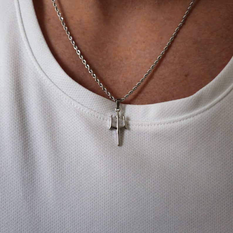 May include: A silver chain necklace with a trident pendant.