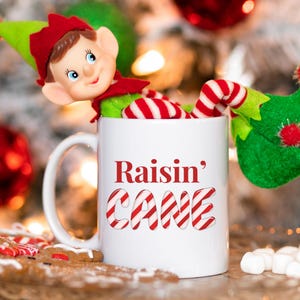 Raisin&#39; Cane Mug, Funny Christmas Ceramic Mug, Holiday Drinkware, Festive Coffee Cup, Winter Season Tea Mug, Xmas Quote Drinkware