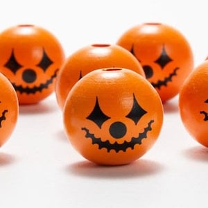 Peut inclure: Huit perles en bois orange en forme de citrouille avec des visages de citrouille noirs.