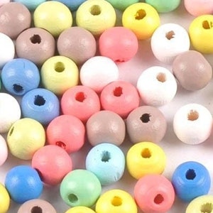 May include: A collection of small, round wooden beads in a variety of pastel and vibrant colours including blue, pink, yellow, green, white, and brown. Each bead features a central hole for threading, scattered across a plain white surface.