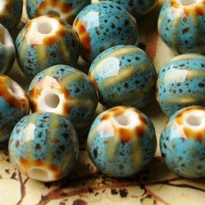 May include: A collection of 15 ceramic beads in shades of blue, brown, and white. The beads have a speckled and striped pattern.