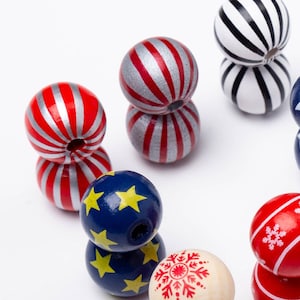 May include: A set of wooden beads with various patterns, including red, white, blue, and snowflake designs. The beads are arranged in a circle on a white background.